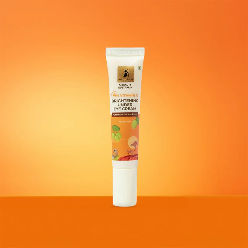 A tube of PILGRIM 4% VITAMIN C BRIGHTENING UNDER EYE CREAM with product information and branding visible orange on background