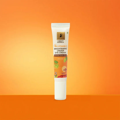 A tube of PILGRIM 4% VITAMIN C BRIGHTENING UNDER EYE CREAM with product information and branding visible orange on background