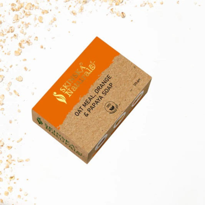 A bar of SKINSKA NATURALS oatmeal, papaya, and orange handmade soap with packaging that has the product name and branding visible.