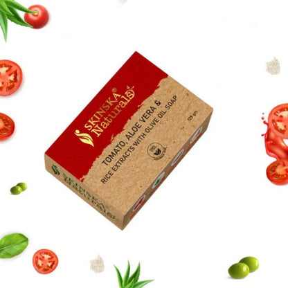A bar of SKINSKA NATURALS handmade soap with tomato, rice extracts, olive oil, and aloe vera, presented with decorative elements like tomatoes and aloe leaves around it.